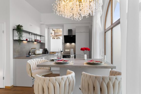 Ferienwohnung Miesbach – Liebelei: Moderne Küche mit stilvollem Essbereich Moderne Küche mit Essbereich, eleganter Beleuchtung und frischen Blumen auf dem Tisch.