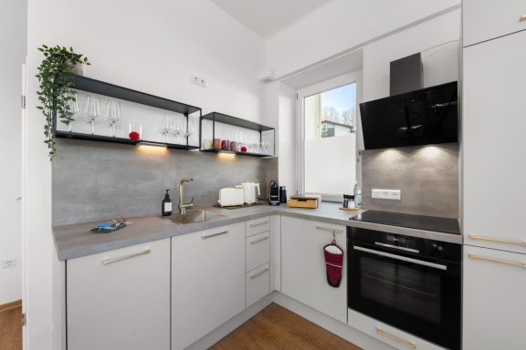 Vollausgestattete Küche in der Ferienwohnung Liebelei in Miesbach Moderne Küche mit grauen Wänden, weißen Schränken und Edelstahl-Geräten.